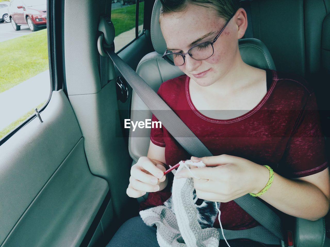 Woman crocheting while sitting in car