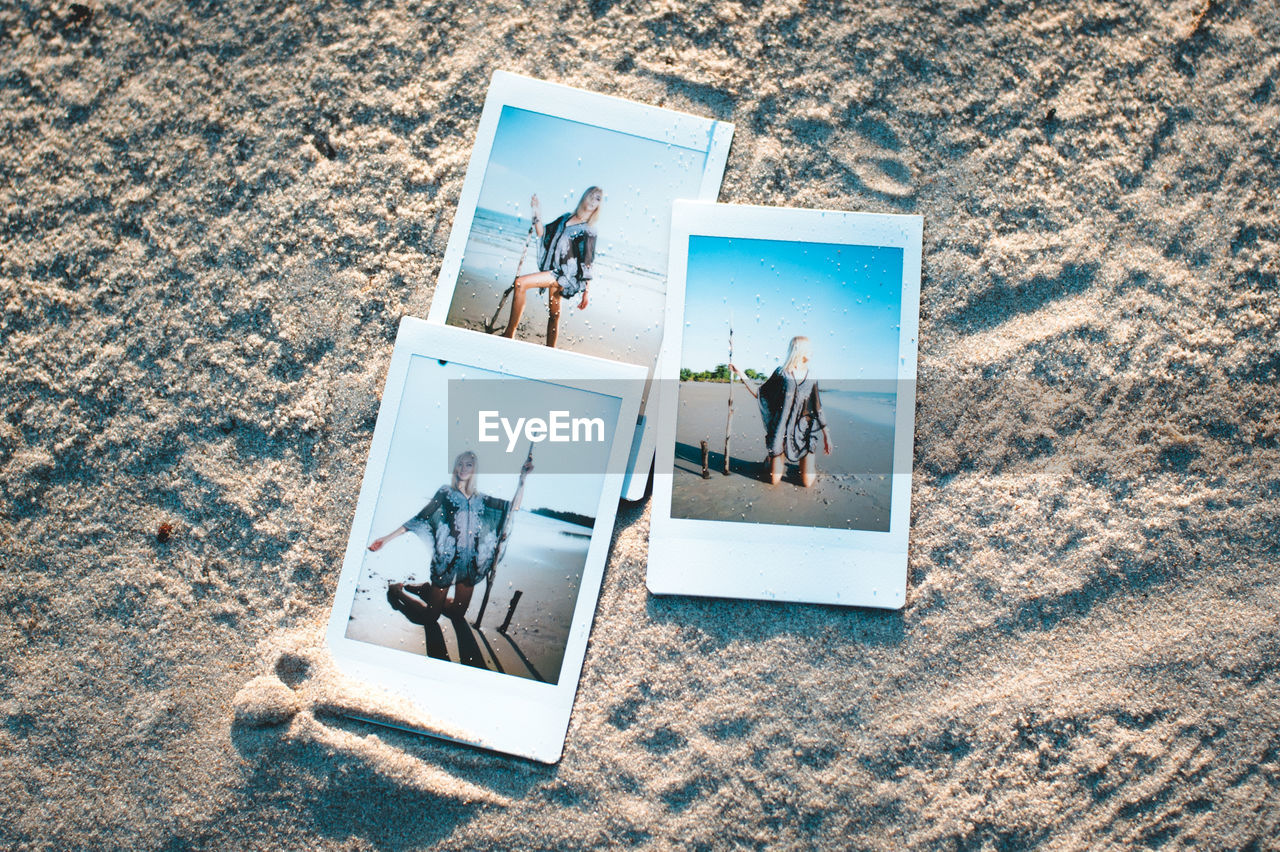 High angle view of photographs on sand