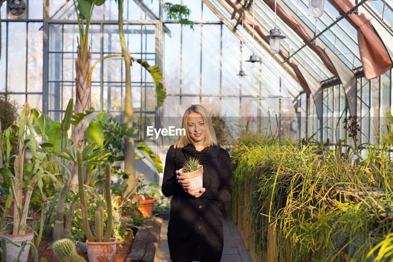 Portrait of smiling woman standing in greenhouse