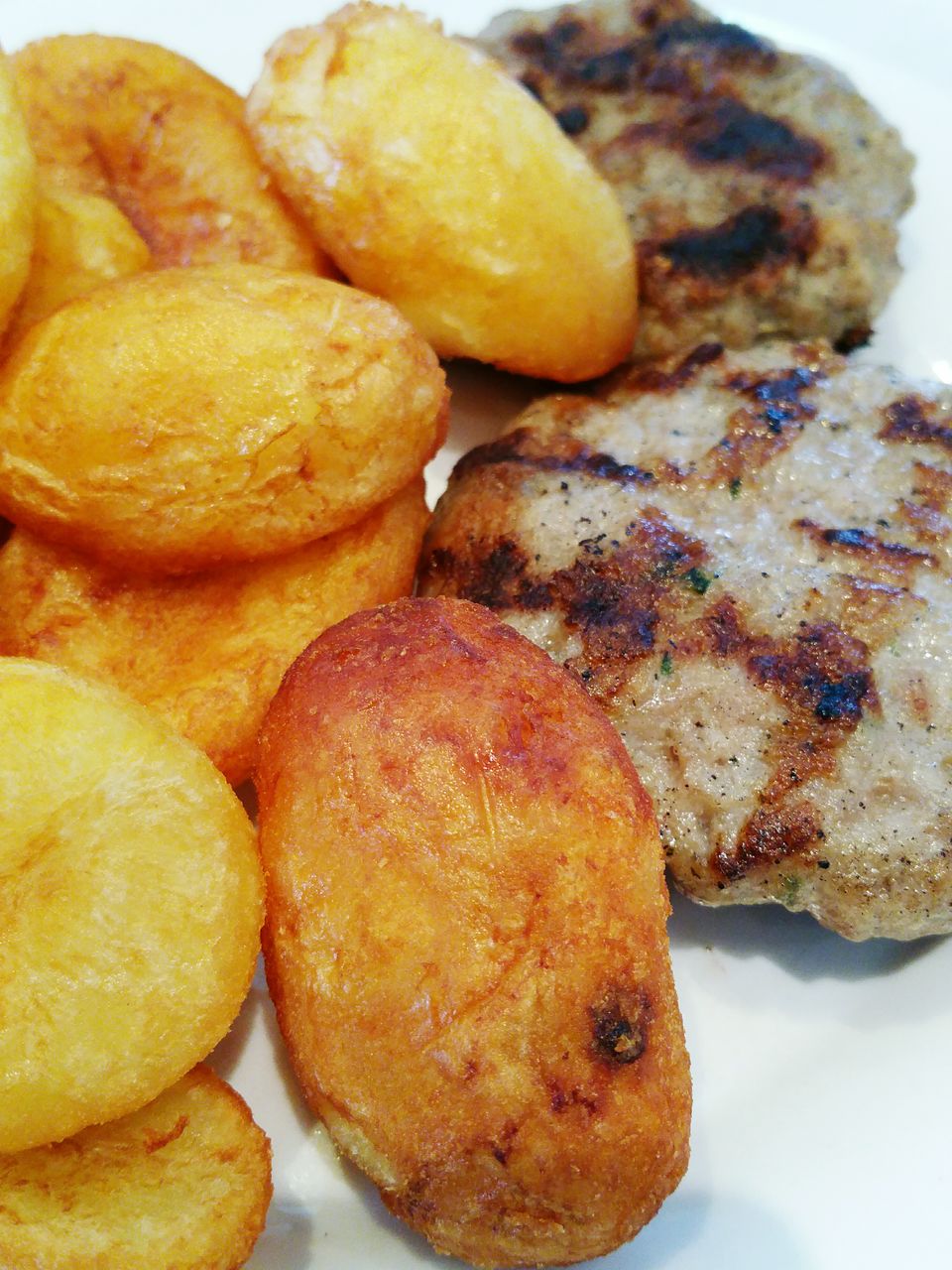 Close-up of fried potatoes and meatballs on table