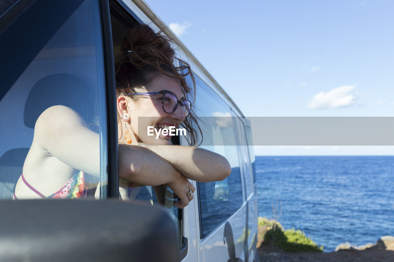 Happy woman looking through window while sitting in motor home