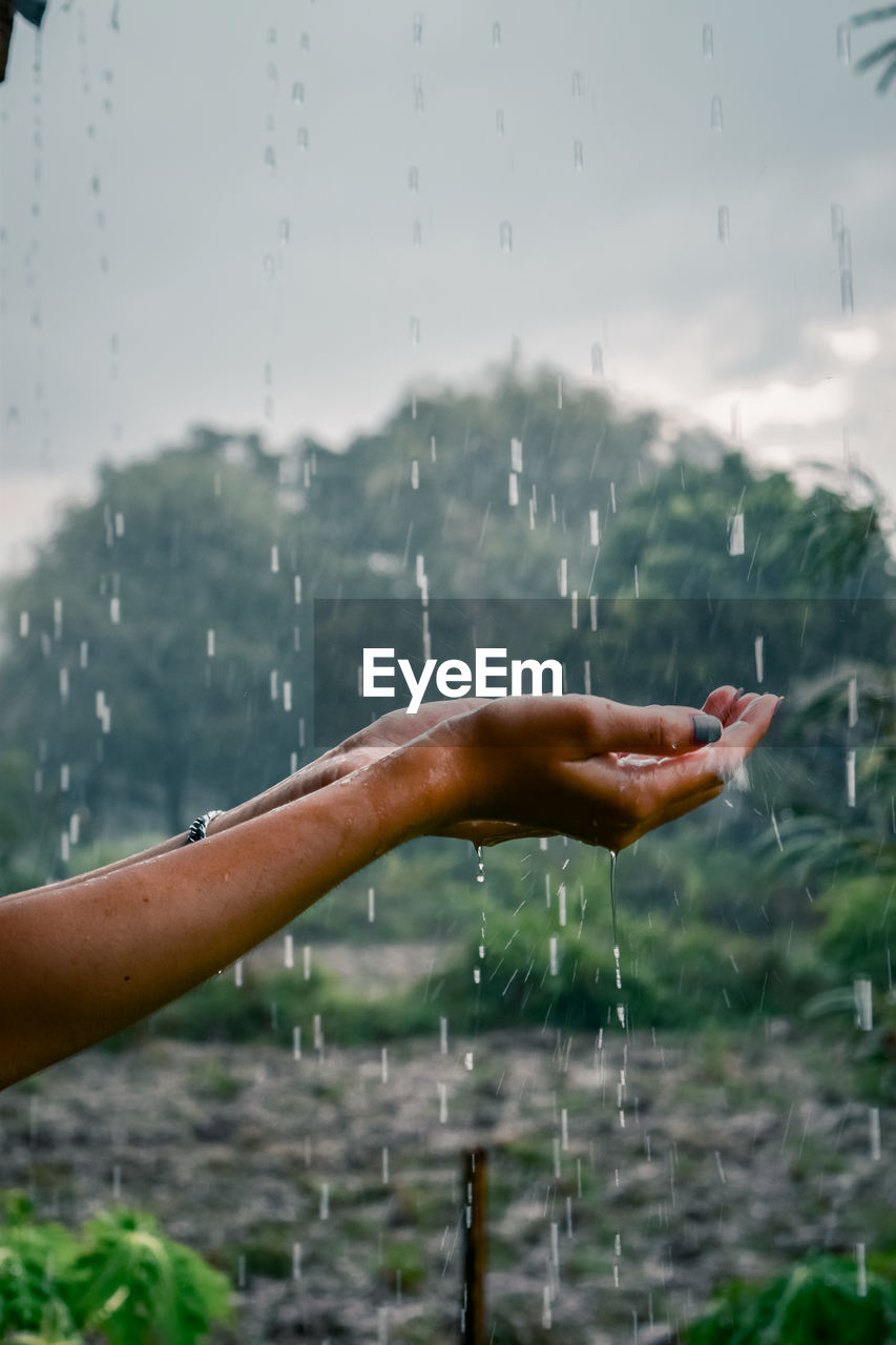 CLOSE-UP OF PERSON HAND IN RAIN
