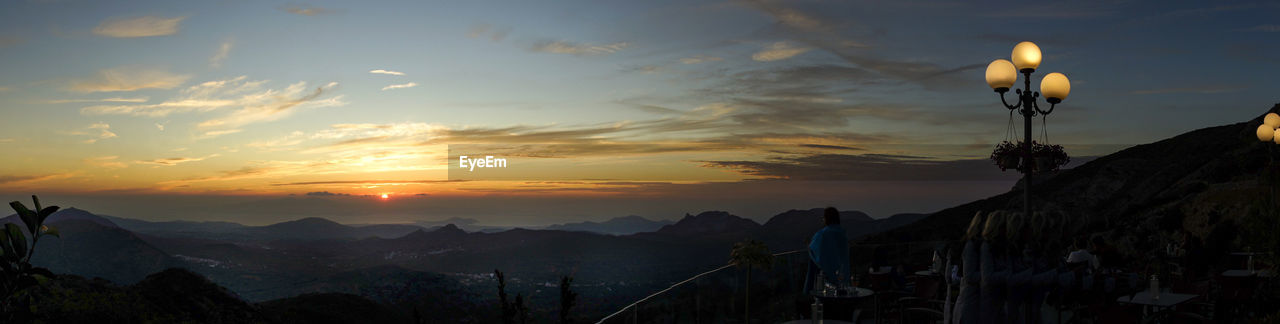 PANORAMIC VIEW OF SILHOUETTE MOUNTAINS AGAINST ORANGE SKY