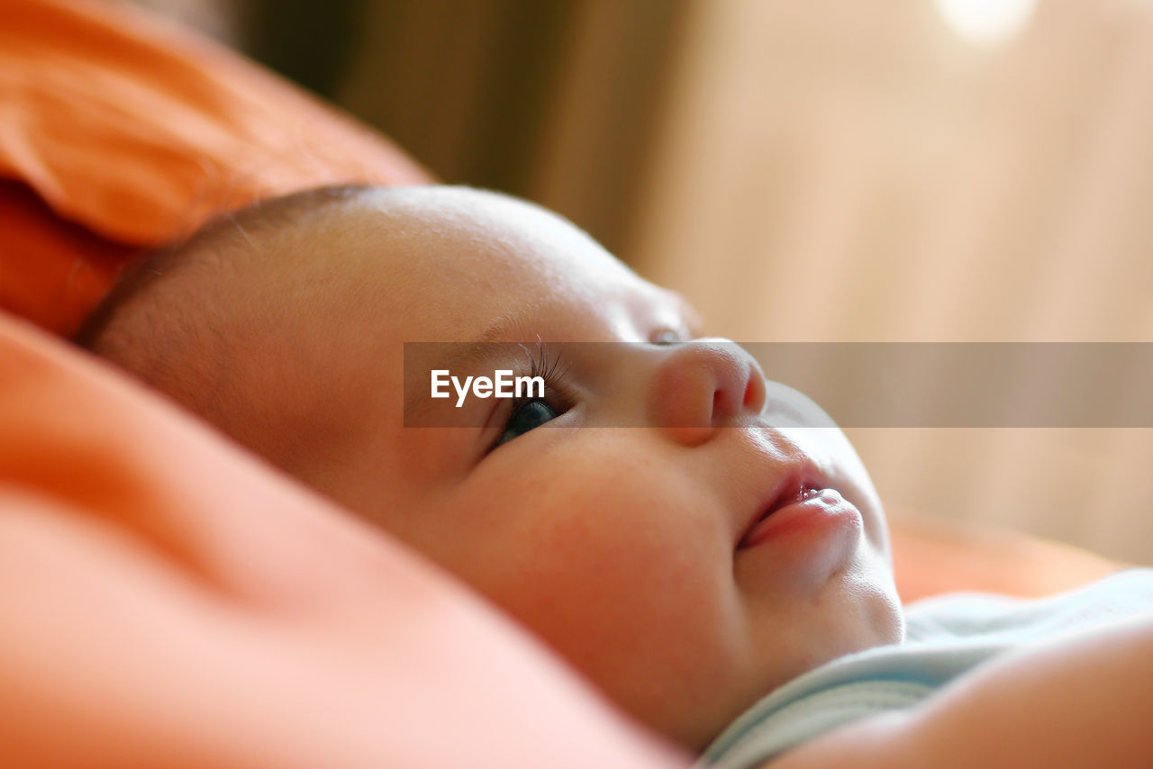 Close-up of cute baby girl lying on bed