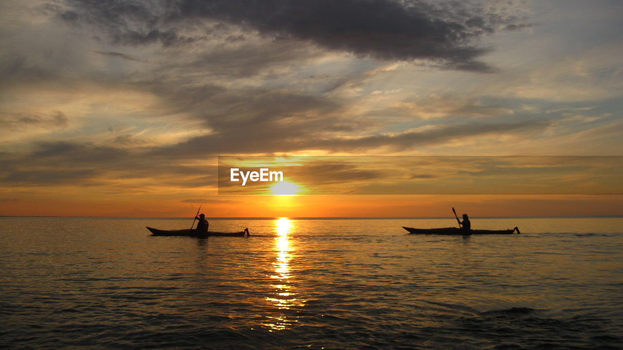 Silhouette people in boat on sea against sky during sunset