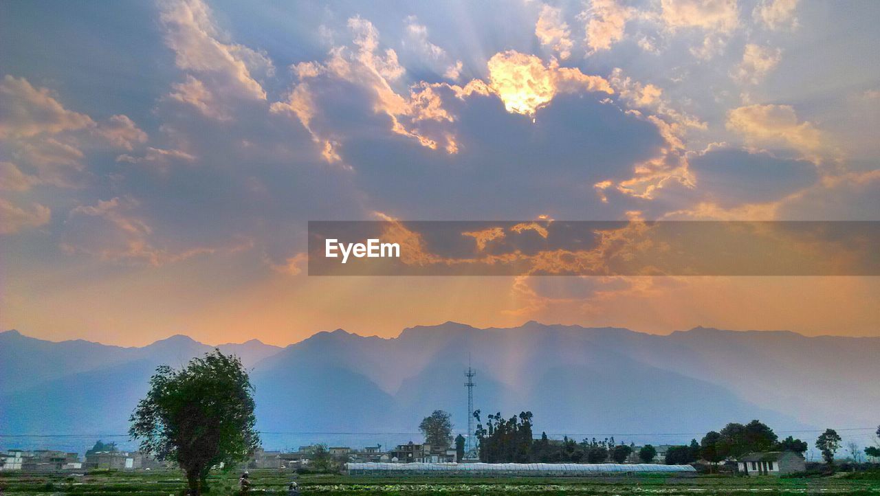 SCENIC VIEW OF MOUNTAINS AGAINST CLOUDY SKY AT SUNSET