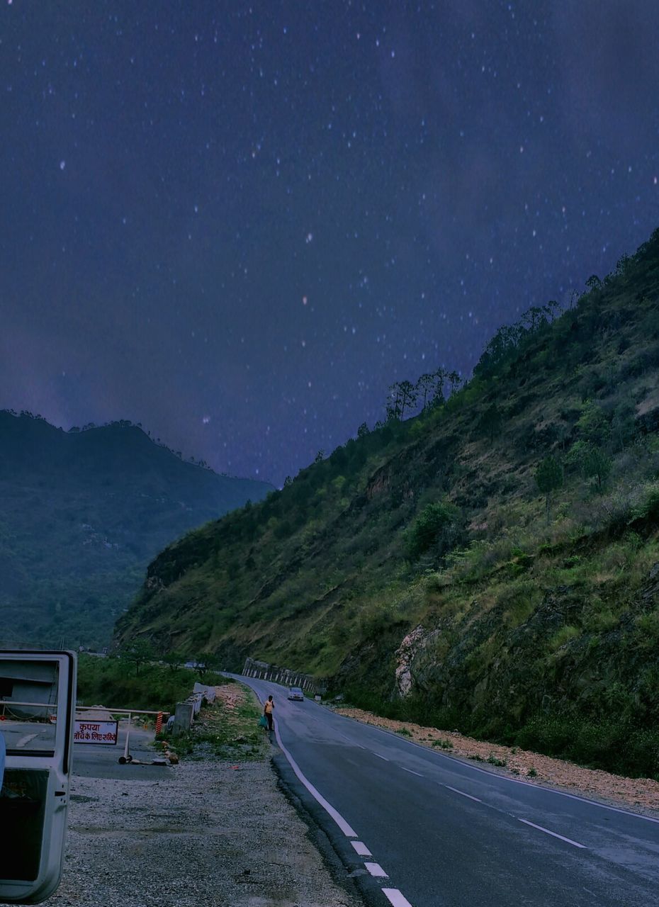 Road by mountains against sky at night