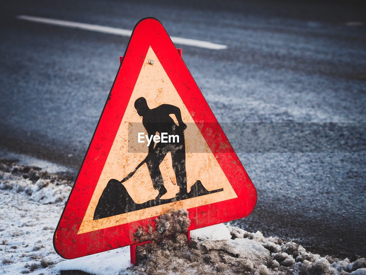 Close-up of men at work sign on road