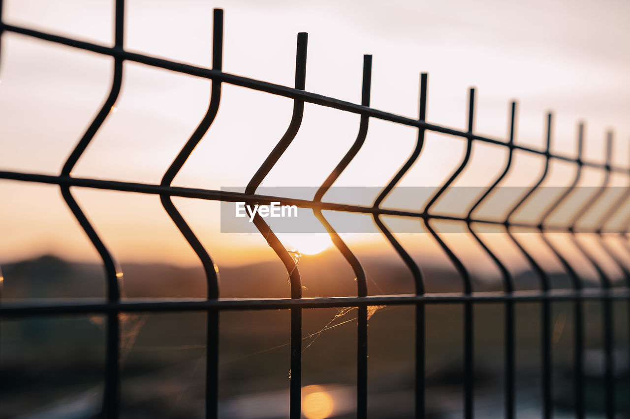 Fence with sunset and web by spider