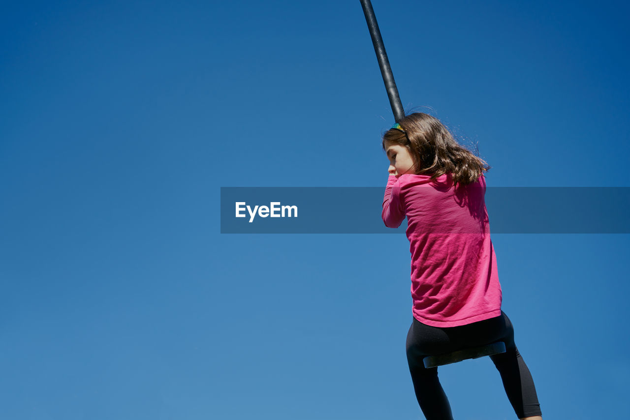 Girl on a children's zip line with a blue sky background