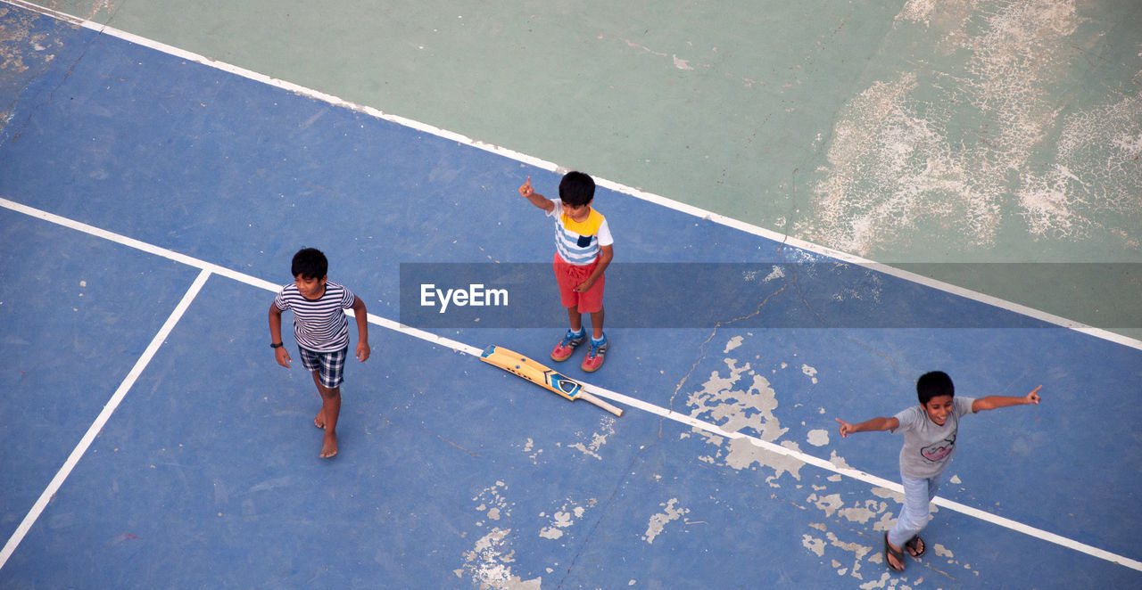 HIGH ANGLE VIEW OF BOYS PLAYING WITH UMBRELLA ON FLOOR