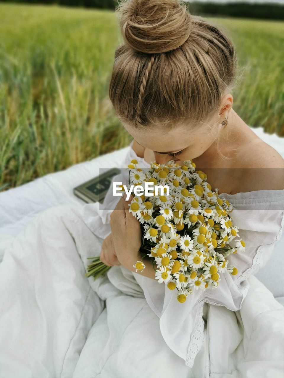 Close-up of bride holding bouquet sitting on grass outdoors