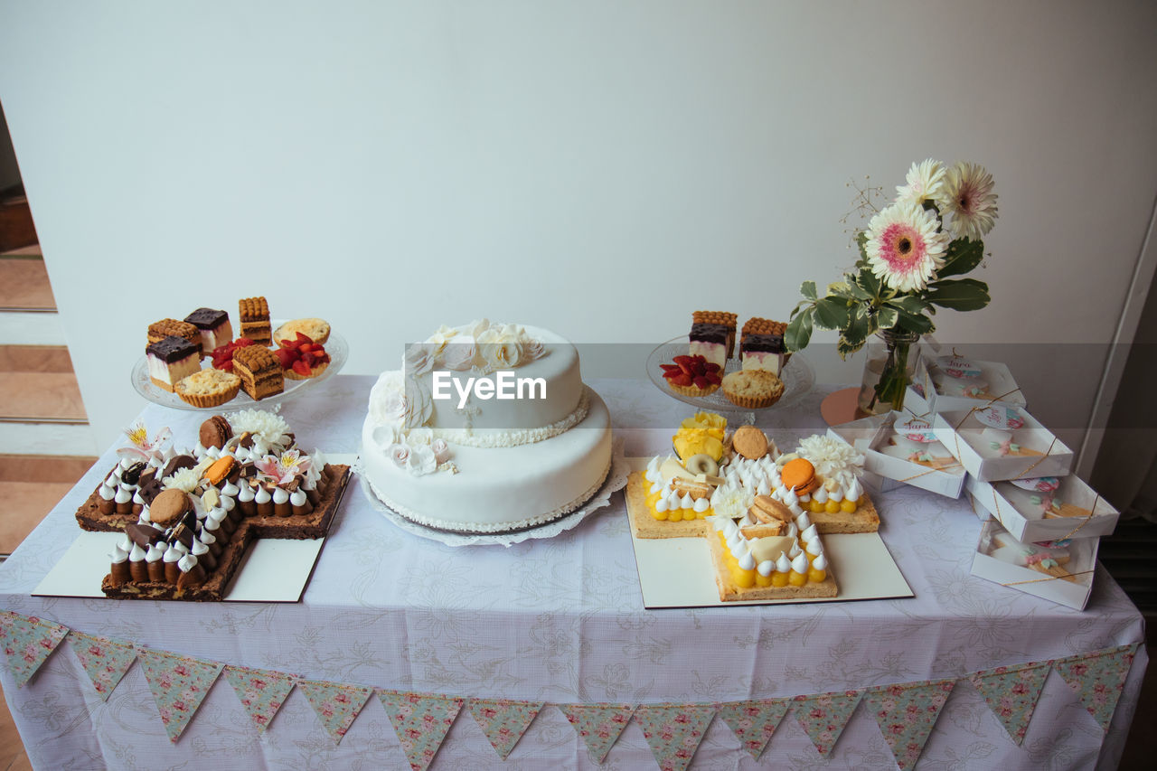 food and drink, food, table, cake, sweet food, flower, dessert, sweet, flowering plant, baked, indoors, freshness, no people, wedding cake, celebration, birthday cake, meal, still life, plant, event, fruit, party, plate, decoration, high angle view, cake decorating, icing, arrangement, tablecloth