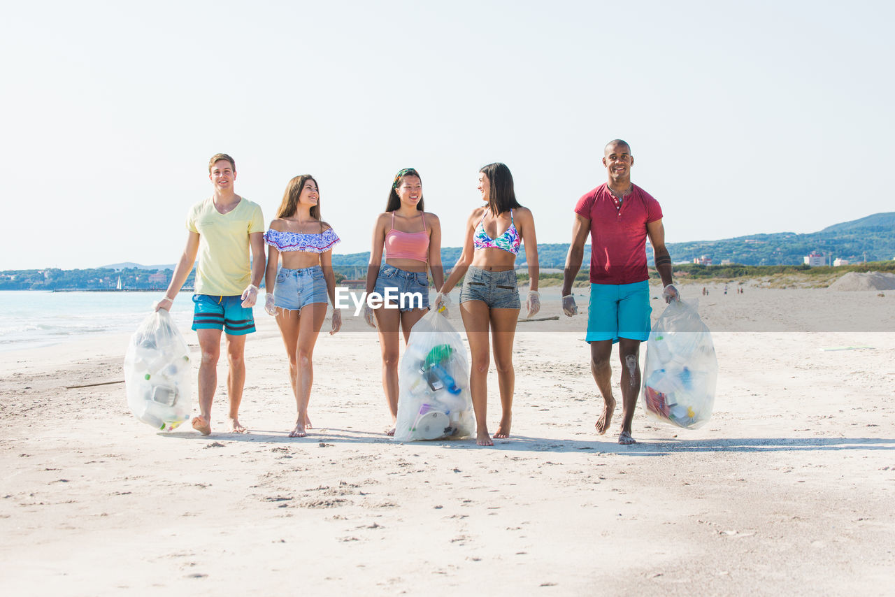 Portrait of activist holding garbage while walking at beach