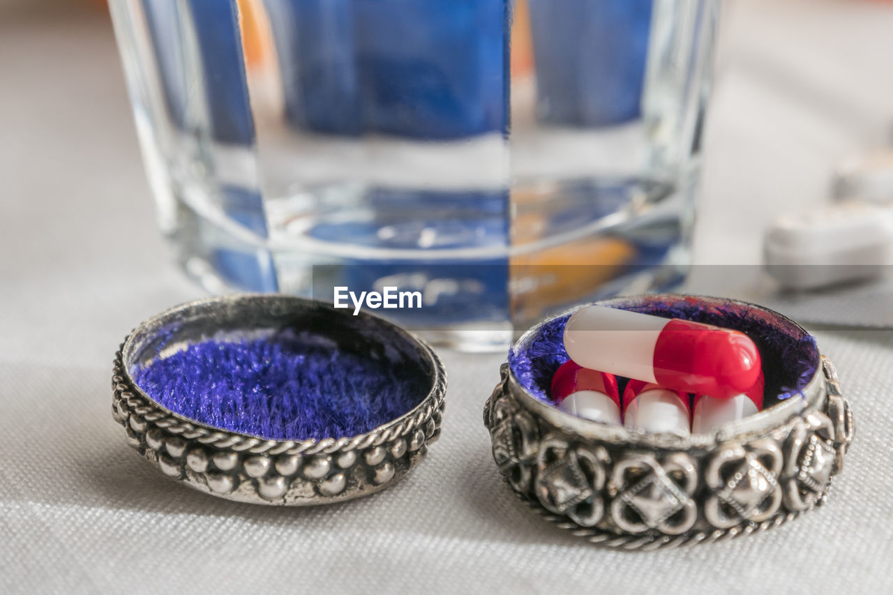 CLOSE-UP OF MULTI COLORED GLASS WITH WATER ON TABLE