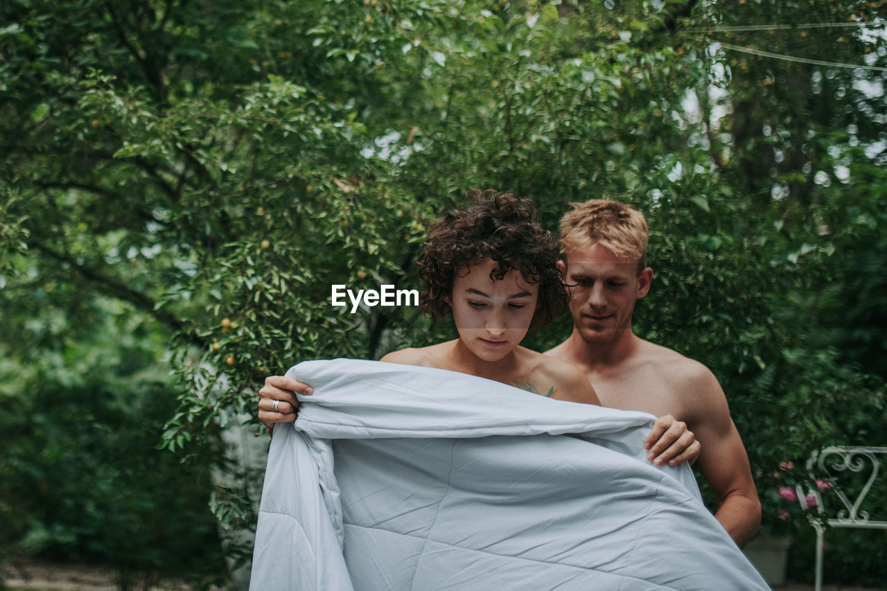 Portrait of couple standing against trees