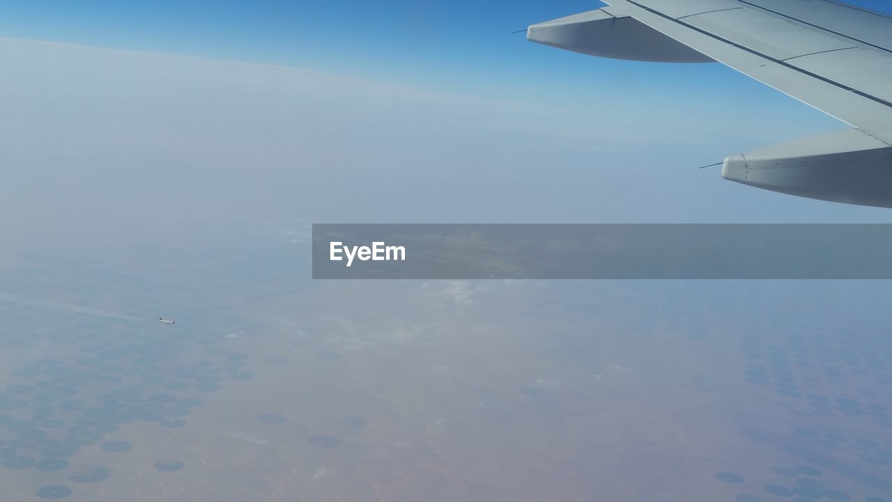 CROPPED IMAGE OF AIRPLANE WING OVER LANDSCAPE