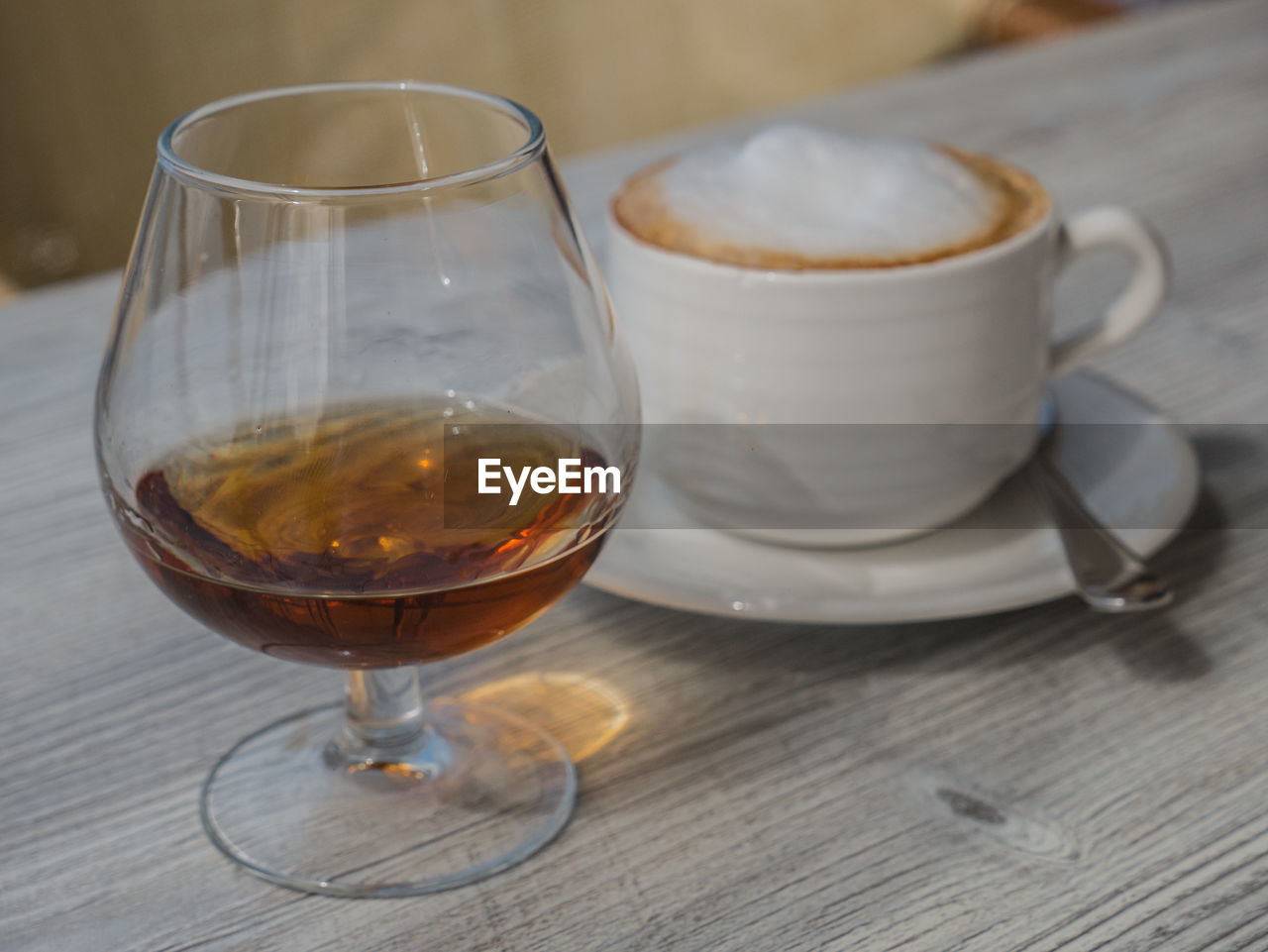 CLOSE-UP OF COFFEE CUP AND WINE ON TABLE