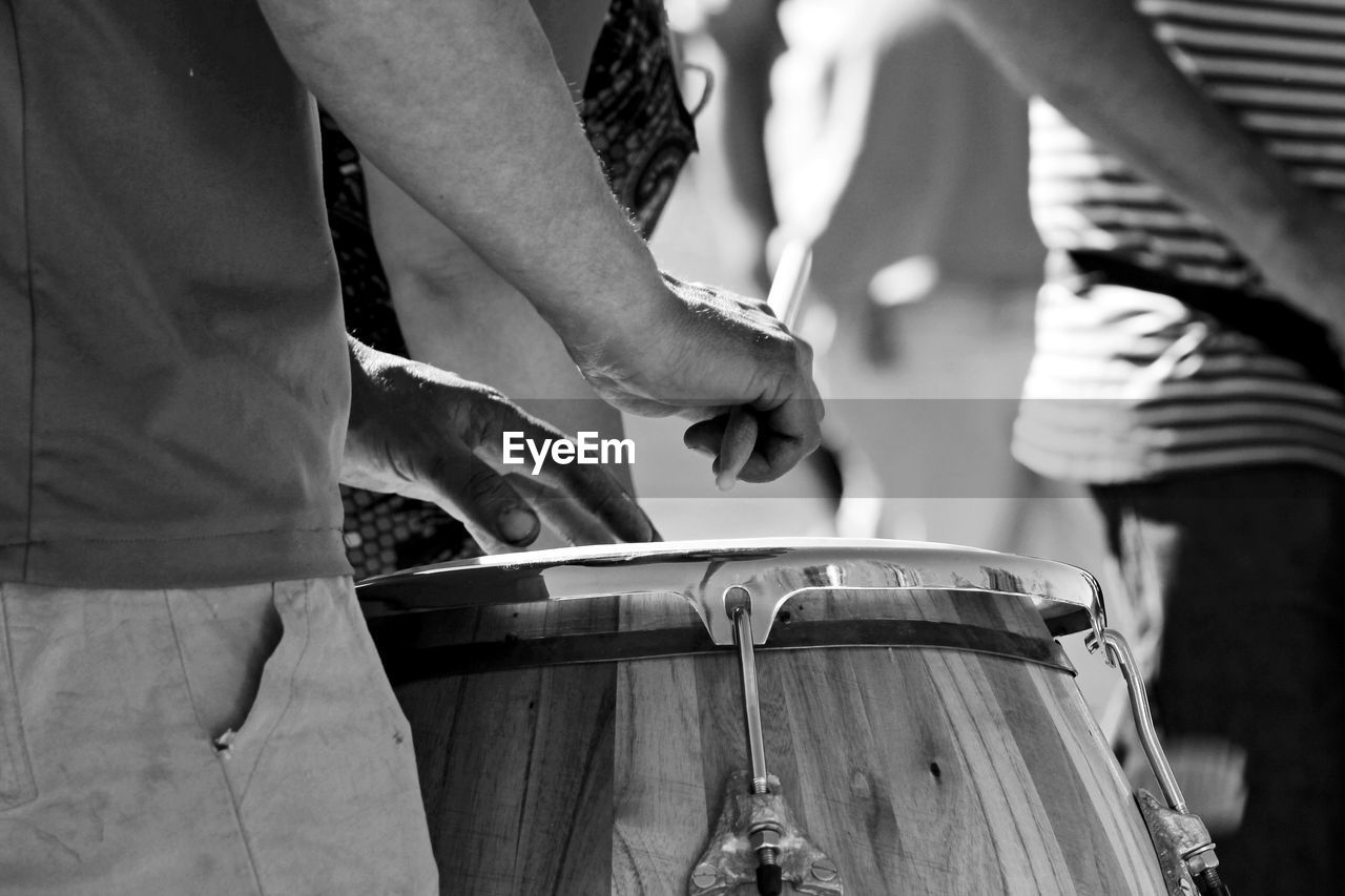 Midsection of man playing drum