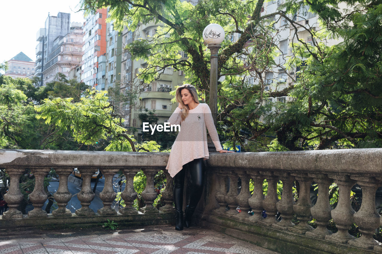 Woman looking away while standing by retaining wall