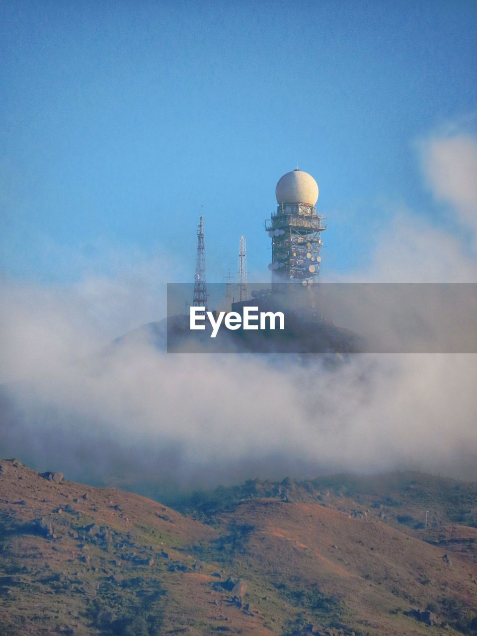 Weather radar station by mountain against sky