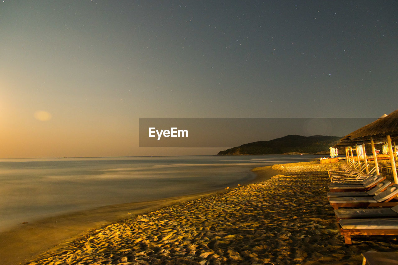 SCENIC VIEW OF BEACH AGAINST SKY AT SUNSET