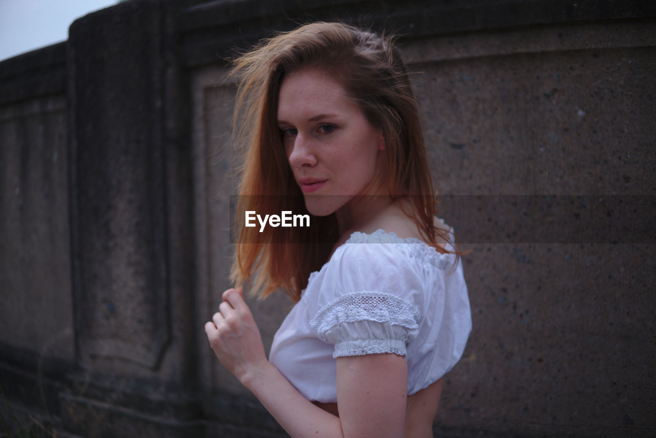 PORTRAIT OF A BEAUTIFUL YOUNG WOMAN STANDING OUTDOORS