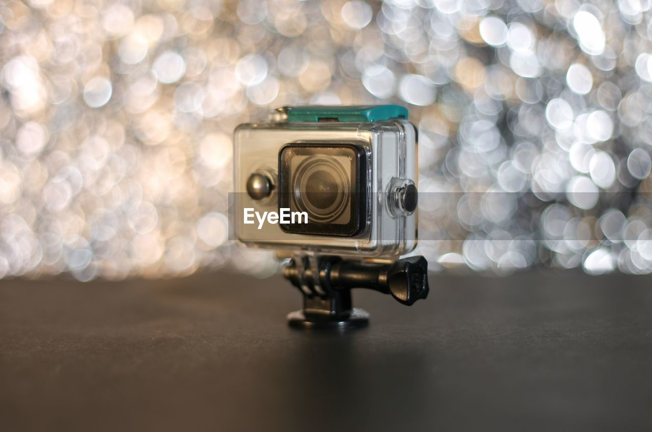 CLOSE-UP OF CAMERA ON TABLE AT ILLUMINATED HOME