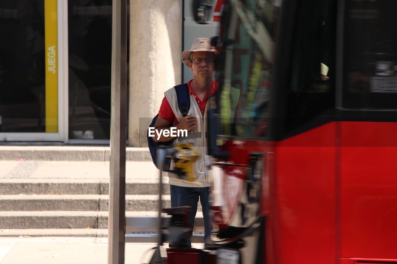 Mature man with backpack standing in front of cable car at city