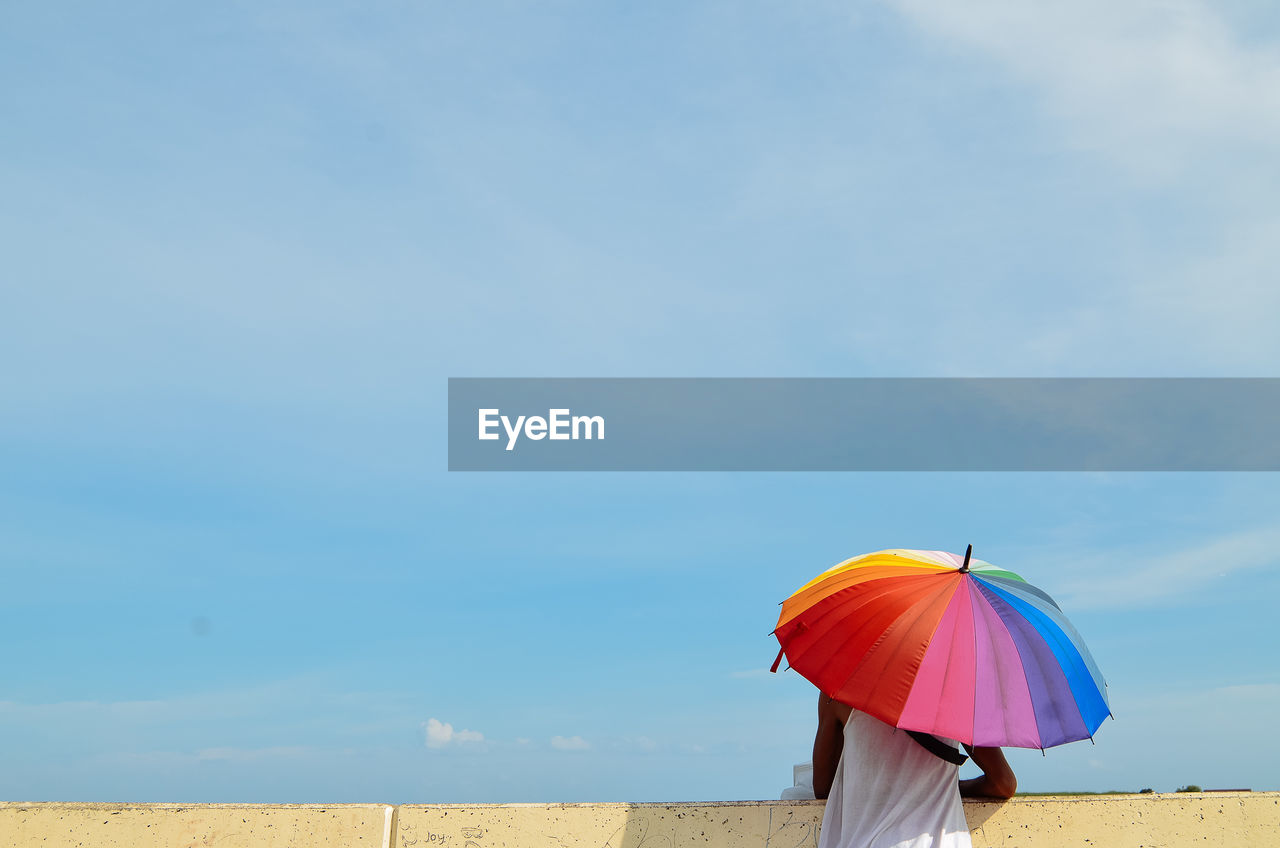 Rear view of woman on beach against sky