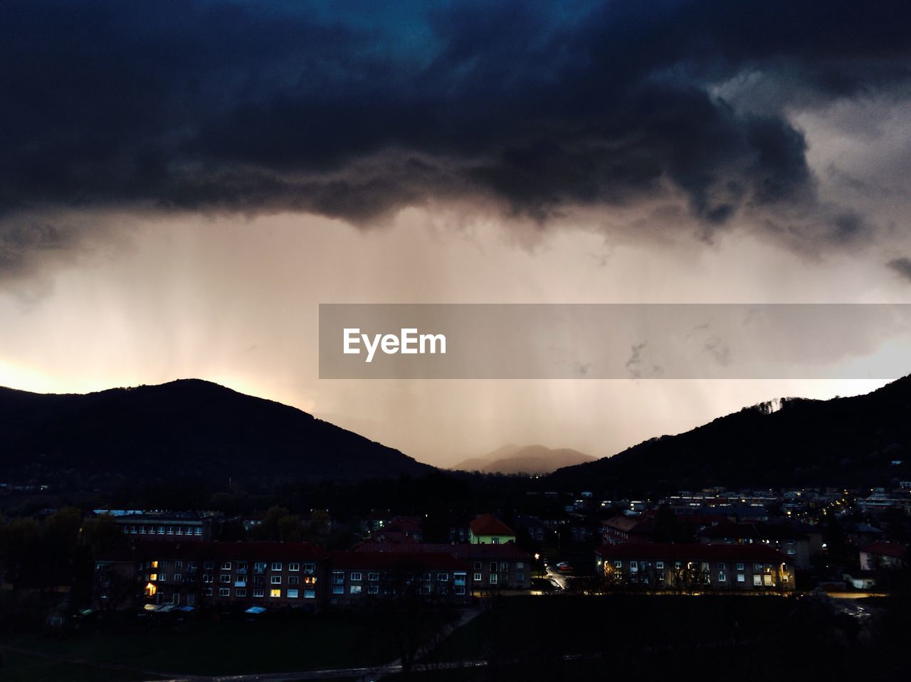 Illuminated cityscape against cloudy sky