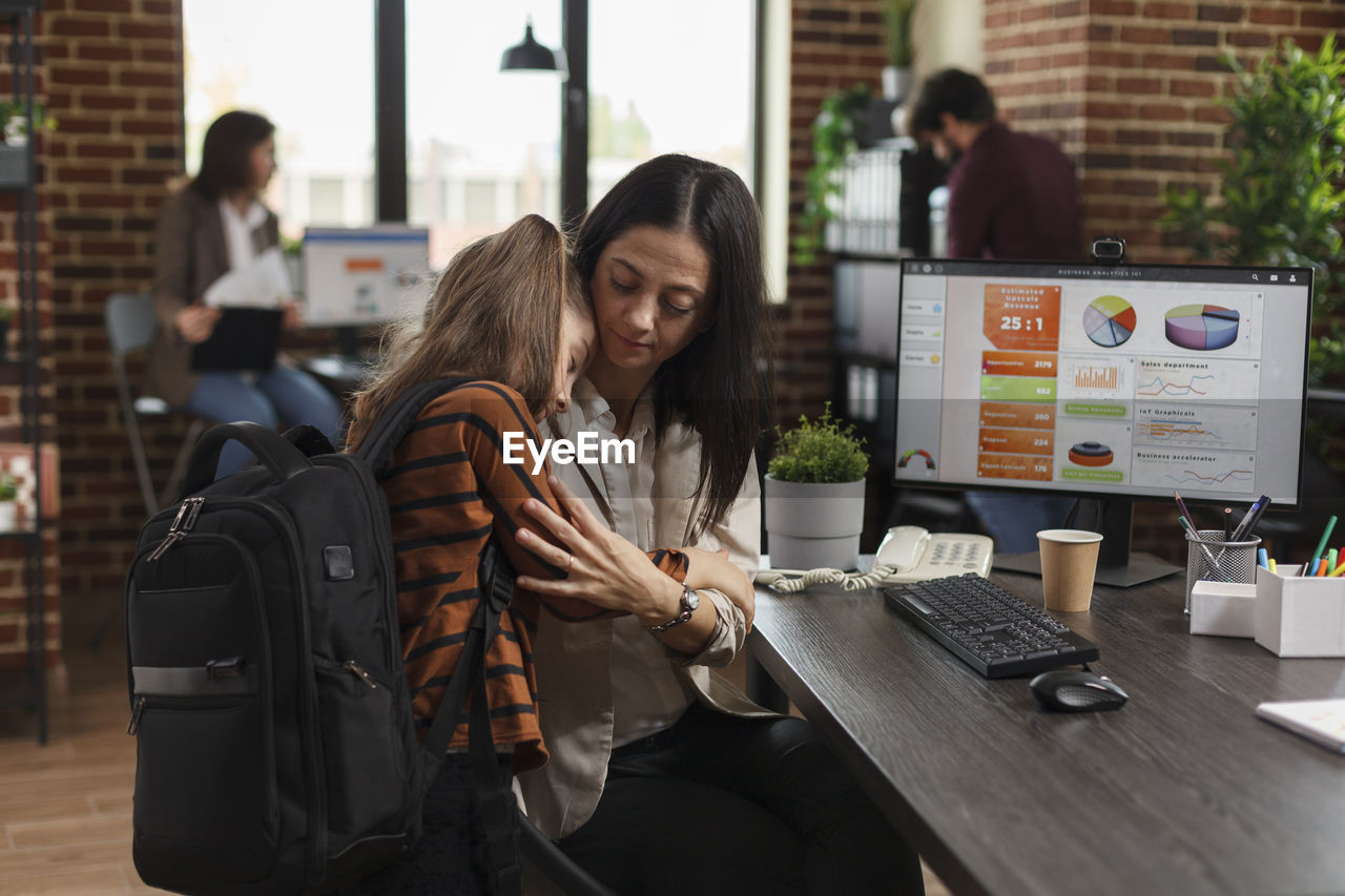 Businesswoman embracing with daughter at office