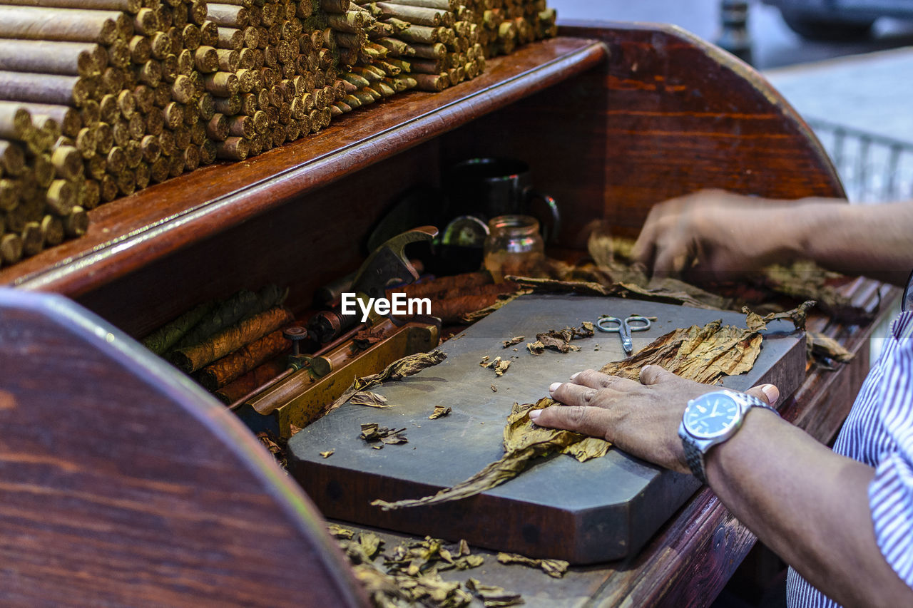 Cropped hands of man making cigars at table