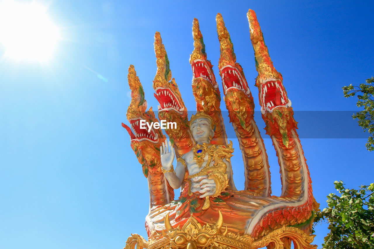 Low angle view of statue against blue sky and building