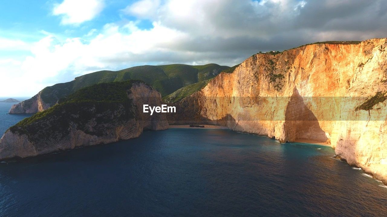 scenic view of sea and mountains against cloudy sky