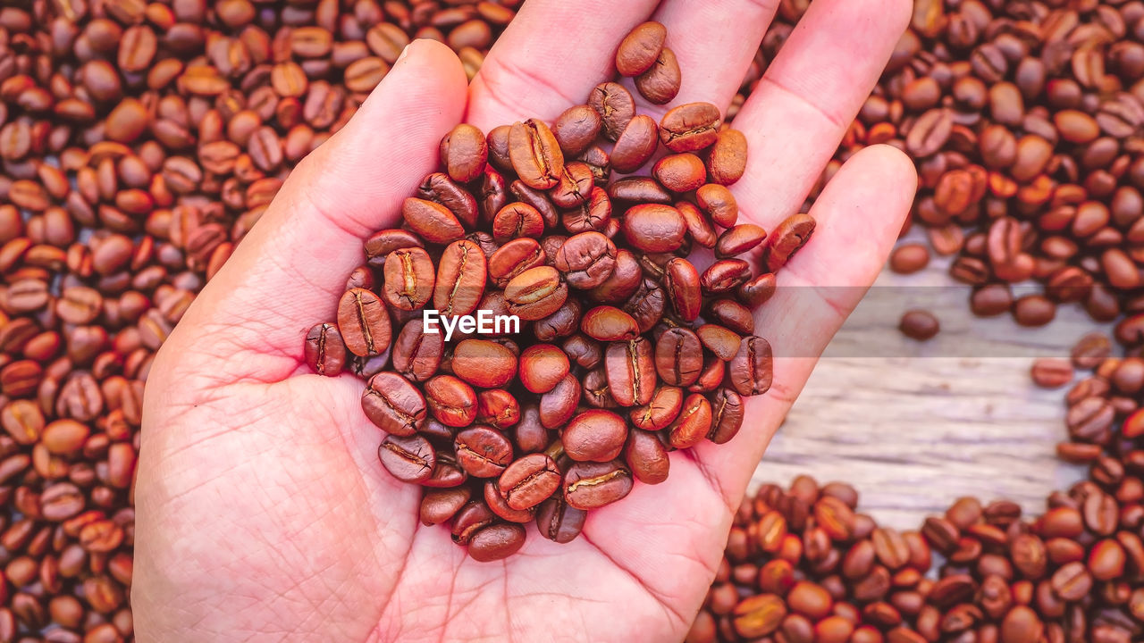 HIGH ANGLE VIEW OF HAND HOLDING COFFEE