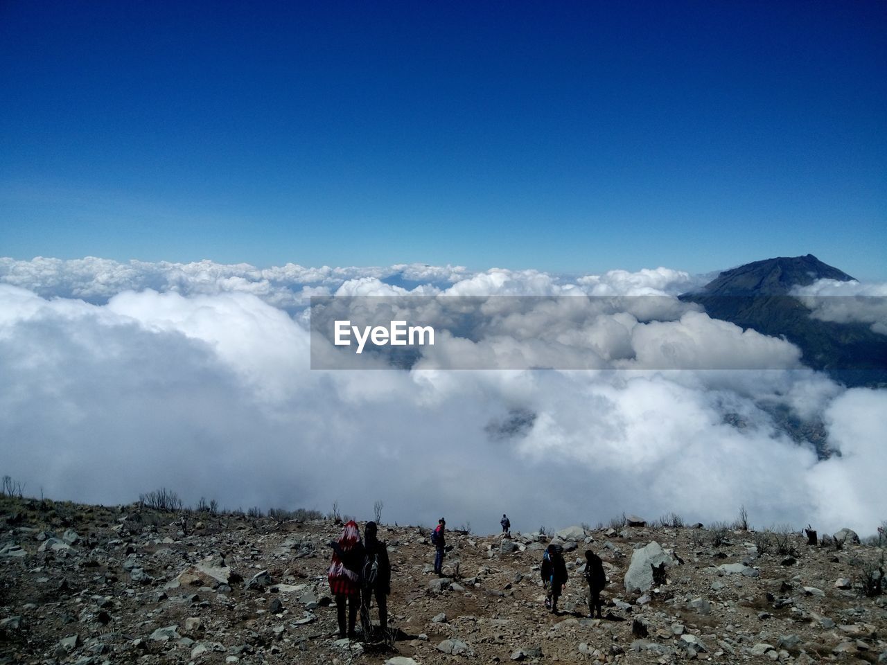 High angle view of people standing on mountain by cloudscape