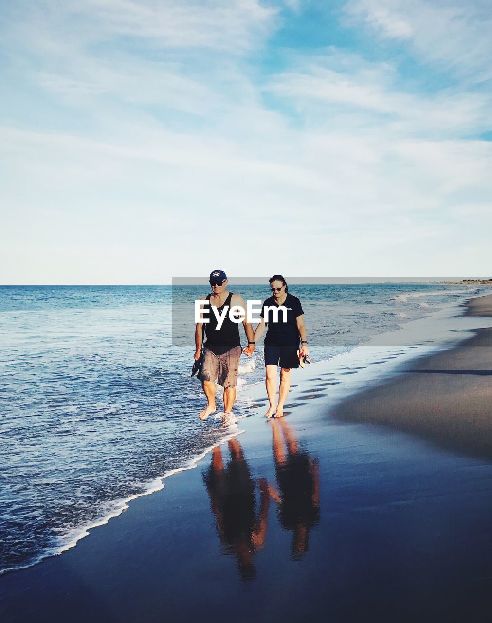 FULL LENGTH OF YOUNG WOMAN ON BEACH AGAINST SKY