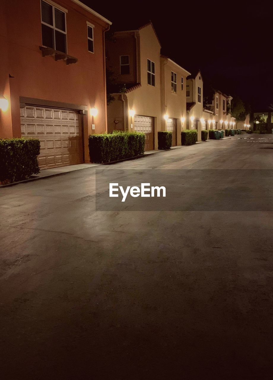 ILLUMINATED STREET BY BUILDINGS AT NIGHT