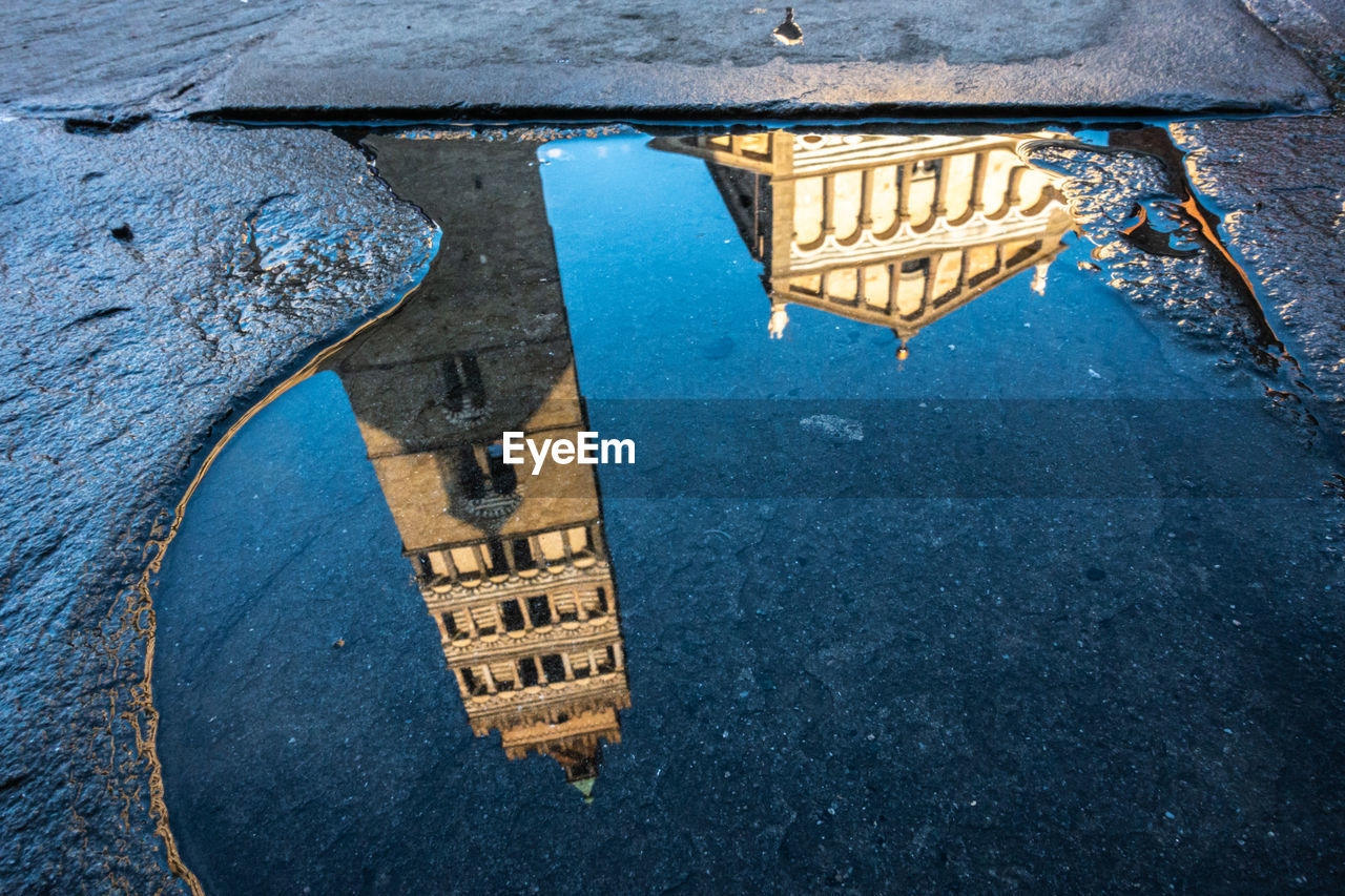 Reflection of building in puddle on street