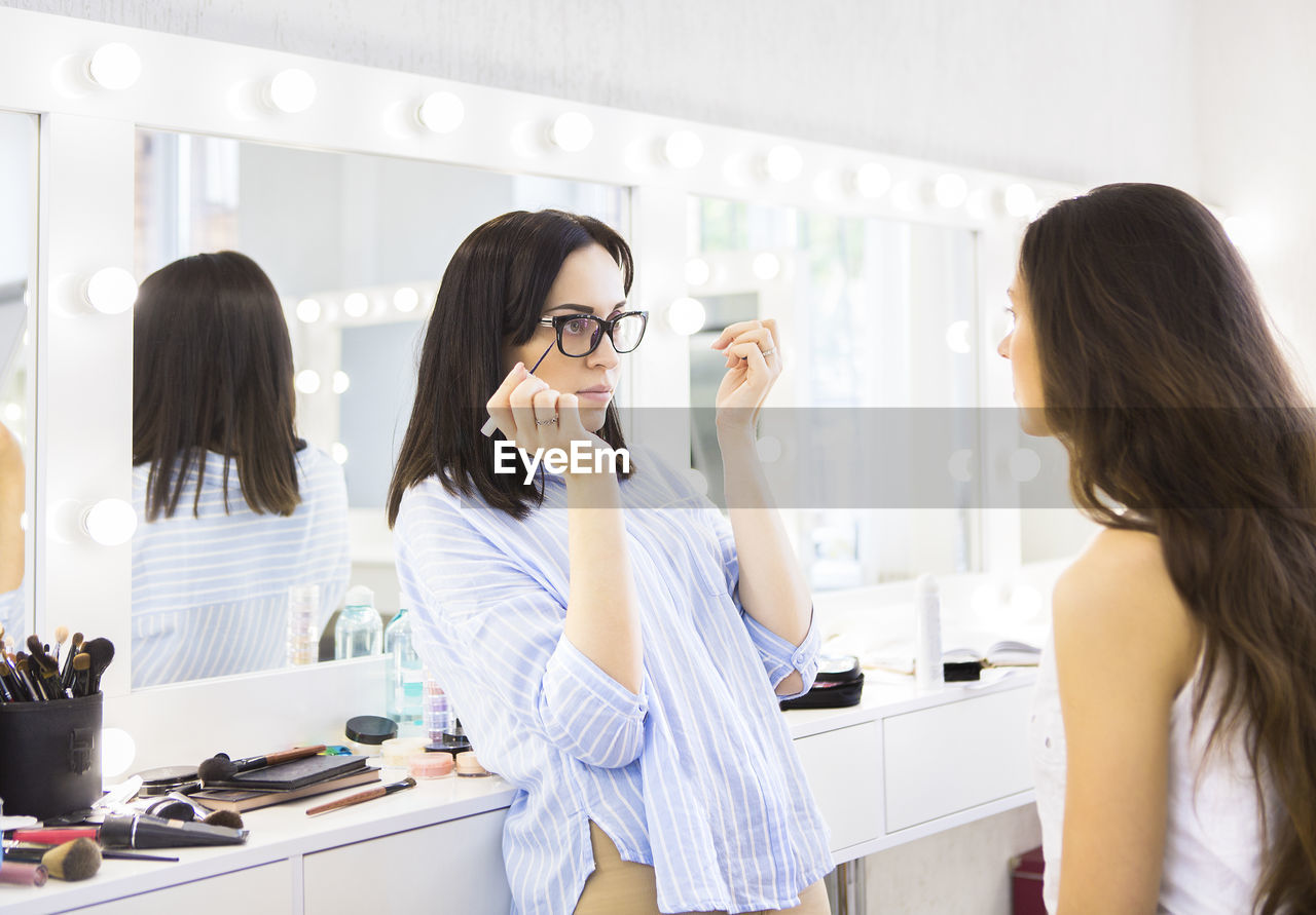 Beautician applying make-up on woman