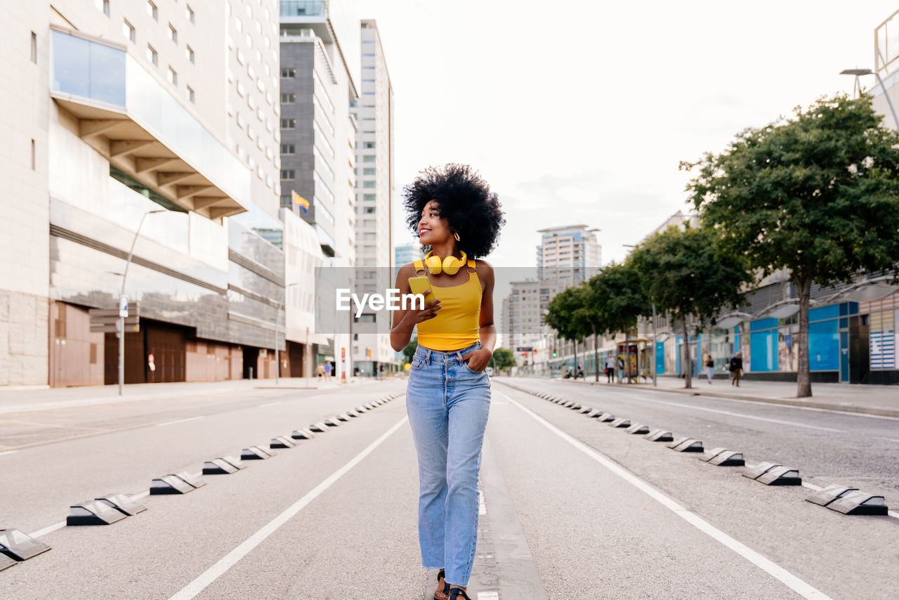 portrait of young woman standing on road in city