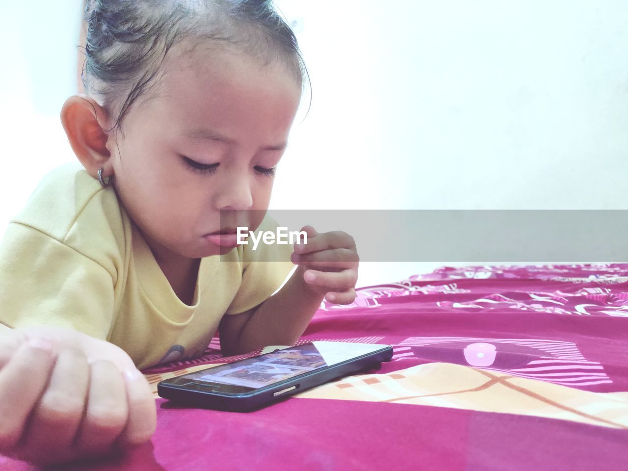 Cute boy using mobile phone on bed