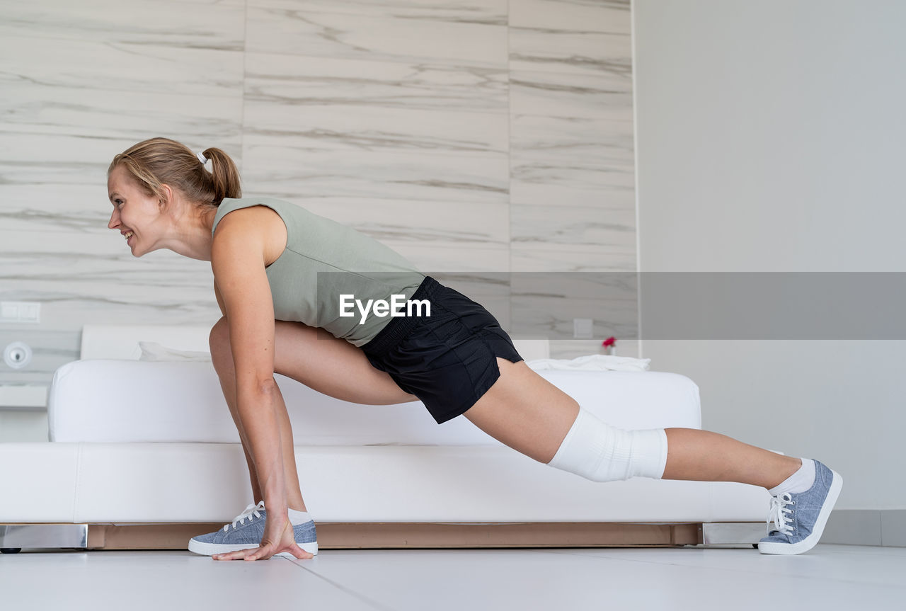 Fitness, home and diet concept. smiling young woman doing lunges at home, in the bedroom