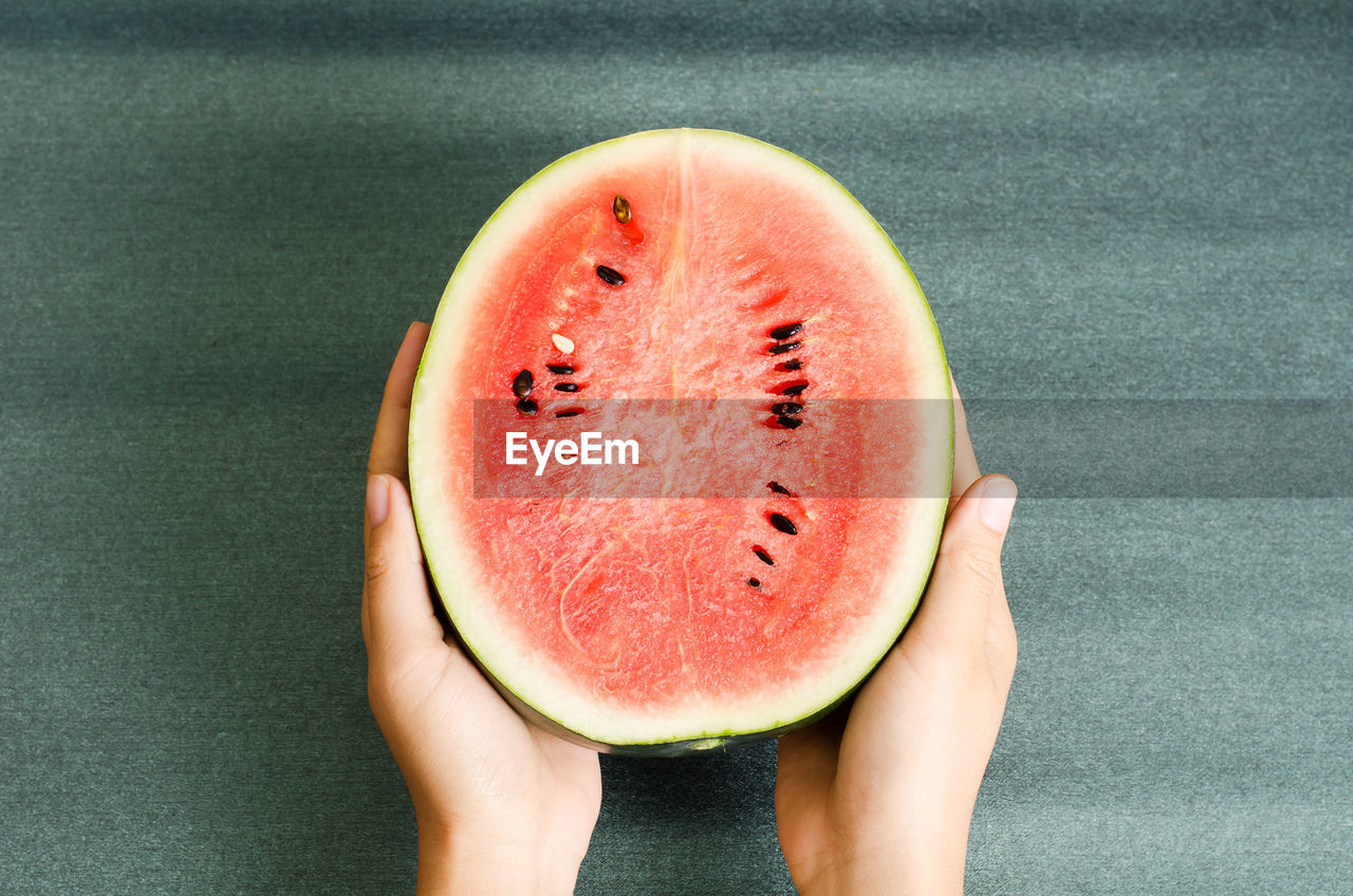 Cropped hands of person holding watermelon on table