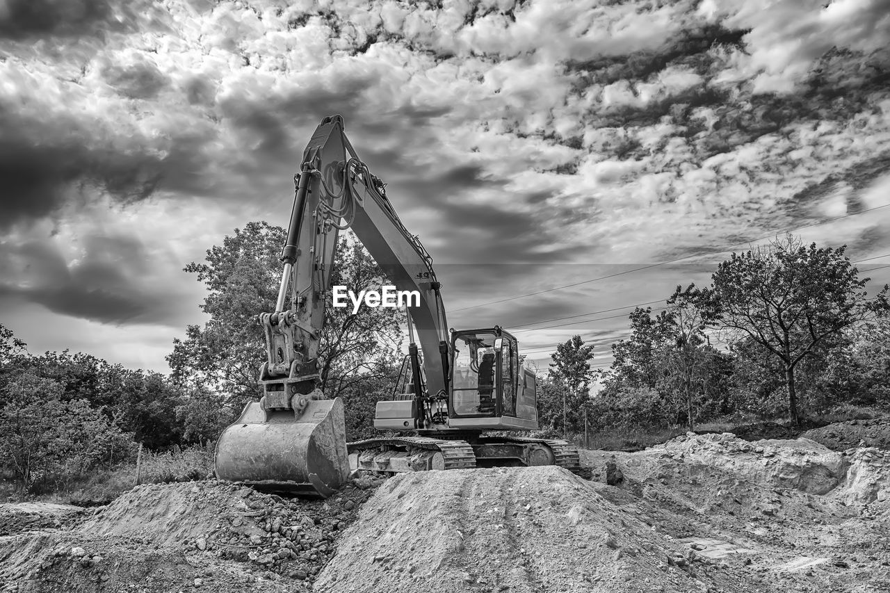 Crawler excavator during earthmoving works on construction site in black and white