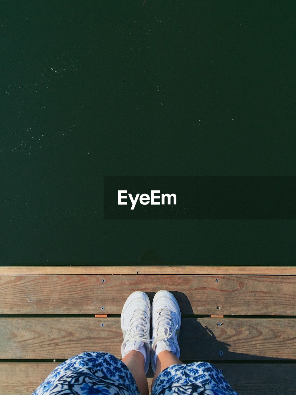 Low section of woman standing on jetty over lake