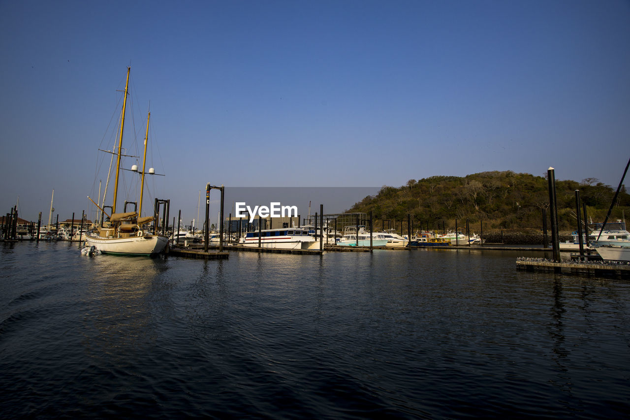 water, nautical vessel, transportation, sky, marina, sea, dock, mode of transportation, sailboat, harbor, reflection, nature, boat, vehicle, ship, mast, no people, bay, clear sky, dusk, architecture, pole, travel, beauty in nature, tranquility, evening, travel destinations, blue, watercraft, outdoors, pier, moored, scenics - nature, sailing, waterfront, yacht, city, tranquil scene, coast, beach, built structure, building exterior, land, port, sailing ship, tall ship, idyllic, day