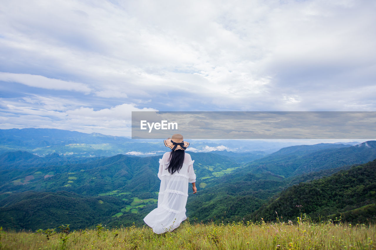 MAN STANDING BY MOUNTAINS AGAINST SKY