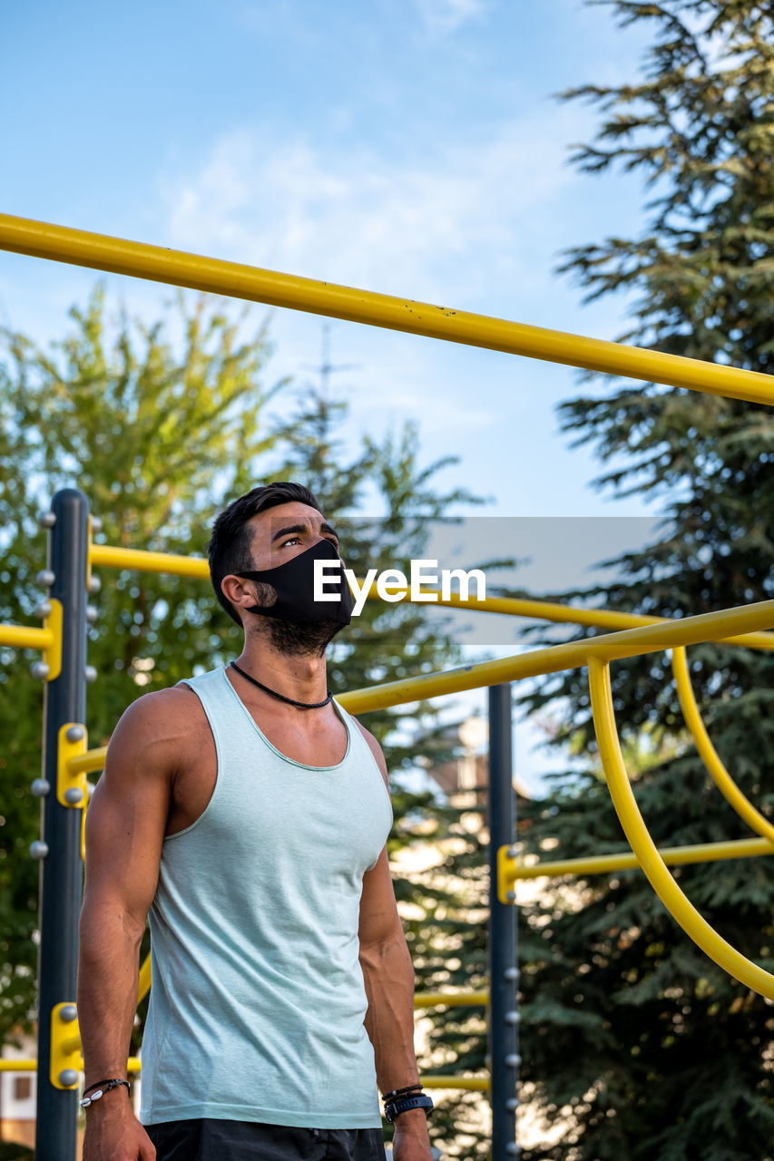 Young man wearing mask exercising outdoors